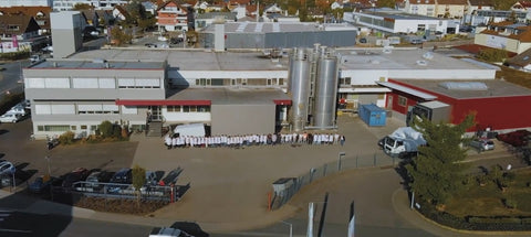 Betriebsgelände von oben mit Sicht auf das Gebäude und die gesamte Belegschaft